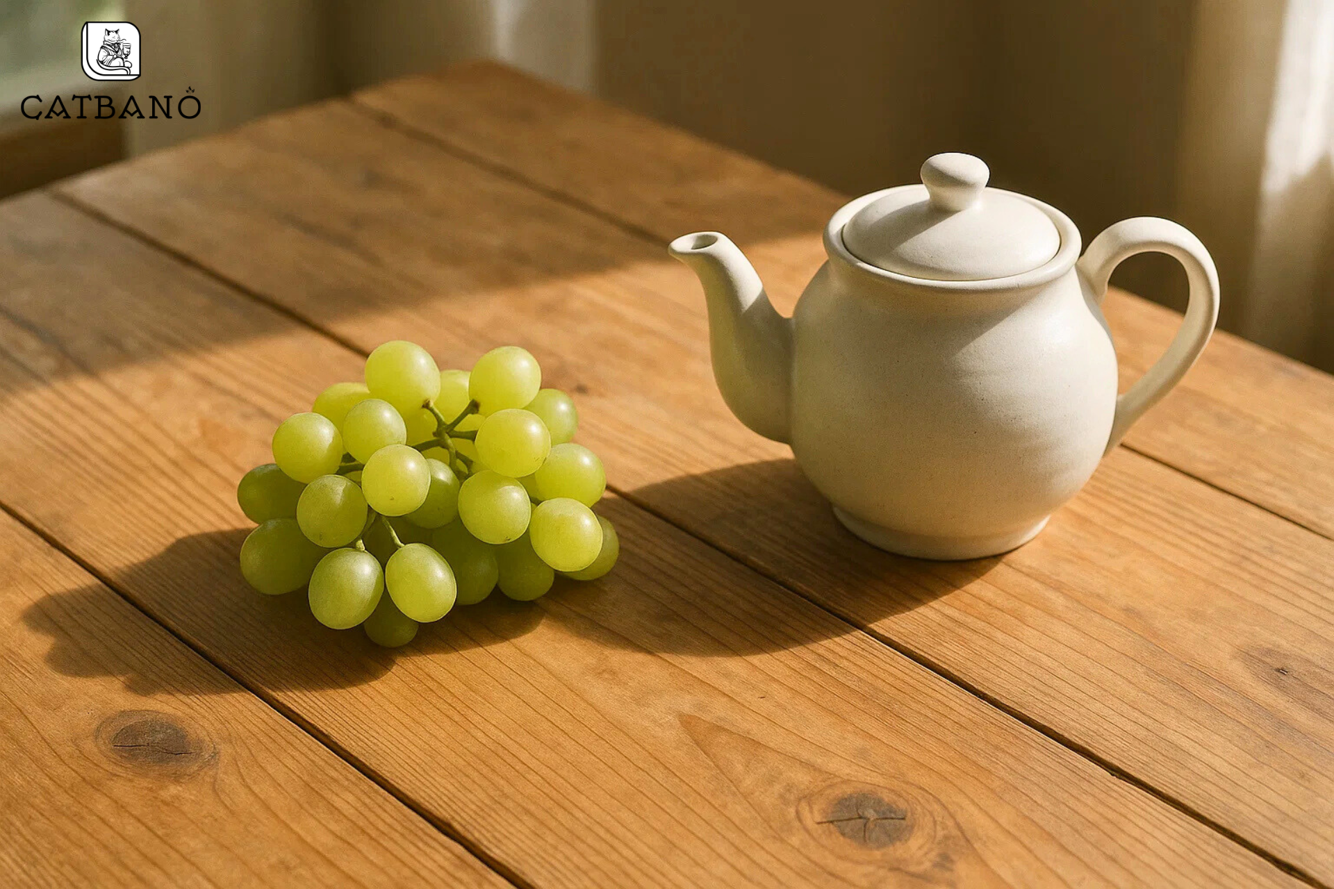 Bàn gỗ với ánh sáng tự nhiên, bên cạnh có chùm nho và bình trà.