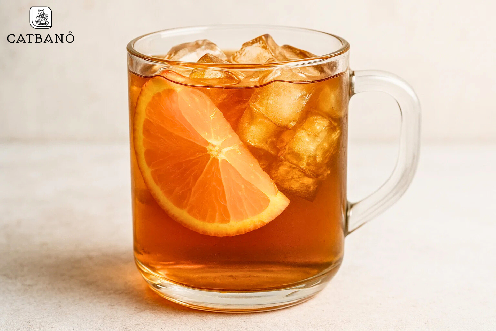 Cốc thủy tinh trong suốt chứa trà màu hổ phách, có lát cam và đá viên.