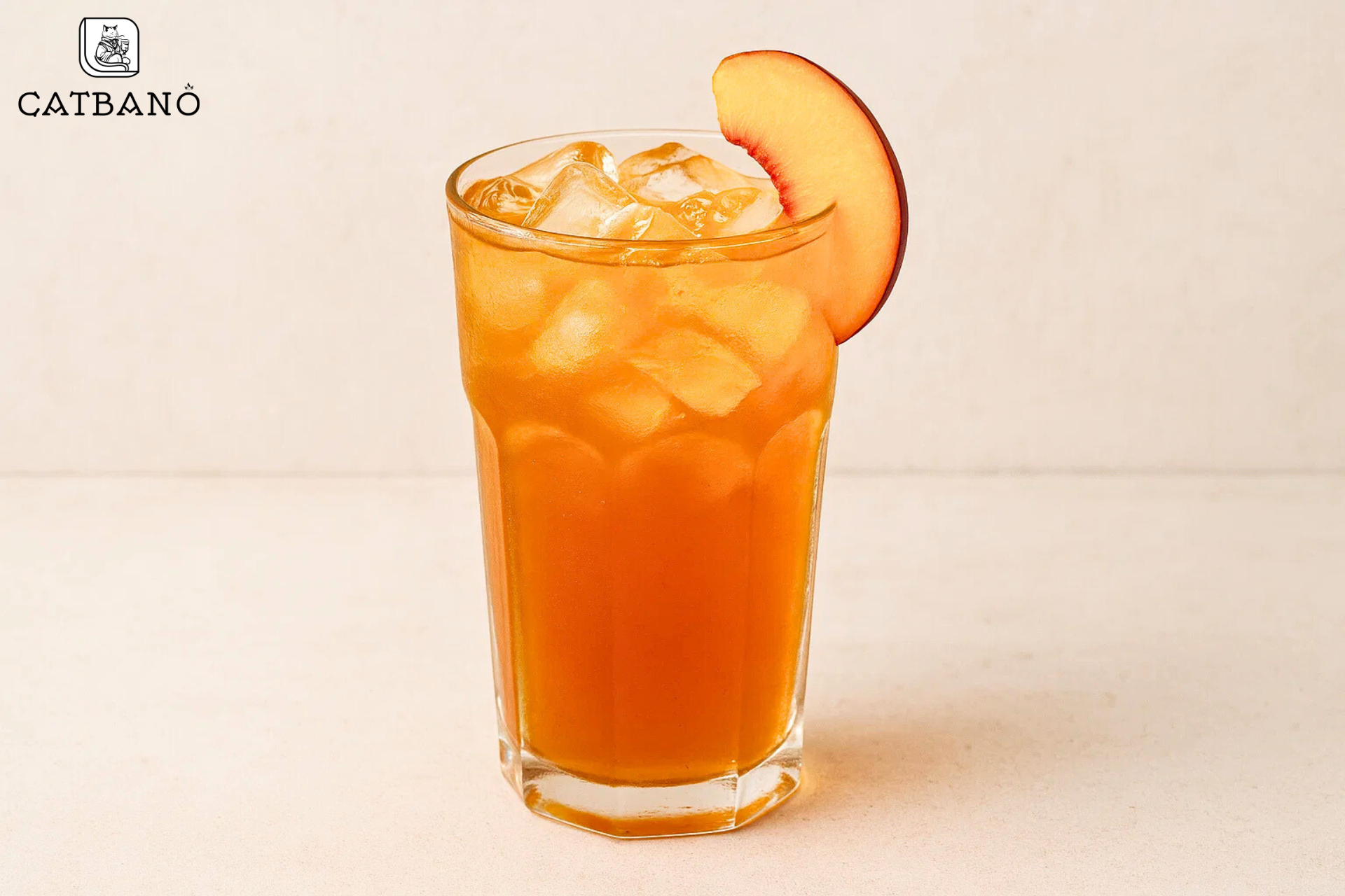 Ly trà Oolong đào vàng cam, lát đào tươi trên miệng ly.